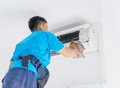 Male technician wiping air conditioner with a cloth