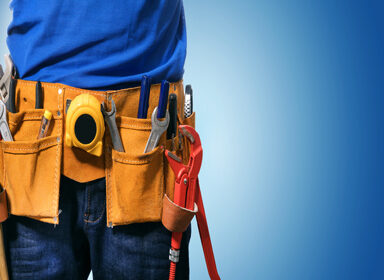 closeup of handyman tool belt on blue background with copy space