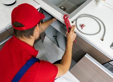 plumbing services - plumber working in domestic kitchen, repairi